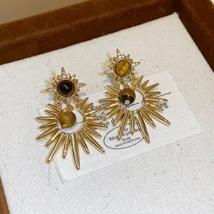 Macro detail of vintage sunburst earrings with tiger eye stone and zircon accents