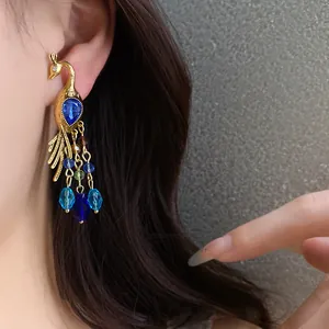 Detalle de pendiente de pavo real bohemio con cristales azules lucido por modelo.
