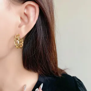 Gros plan de créoles en chaîne plaquées or avec zircons brillants portées par un mannequin.