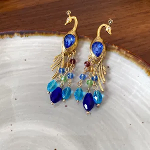 Detalle de pendientes de pavo real bohemios con piedras azules y cuentas multicolores.