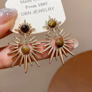 Macro shot of retro starburst earrings with tiger's eye and zircons on a display card