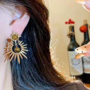 Close-up of vintage Maillard style sunburst earrings featuring tiger's eye stones on an ear.