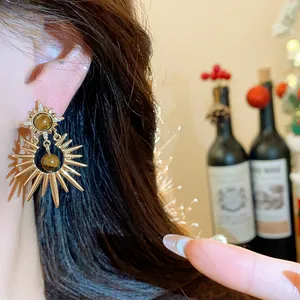 Detailed view of vintage gold sunburst earrings with tiger eye stone and zircons.