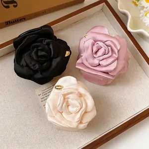 Elegant satin rose flower hair shark clips in three colors for women on a tray