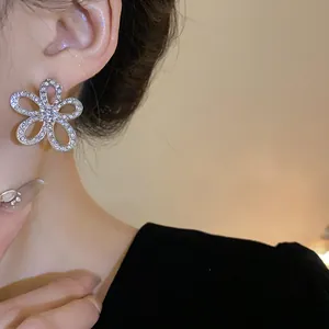 Dettaglio di squisiti orecchini a fiore con strass indossati da una modella asiatica