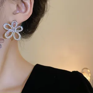 Dettaglio ravvicinato di orecchini a lobo a fiore con strass indossati