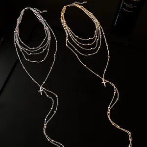 Detailed view of gold and silver layered necklaces with zircon cross pendants on black.