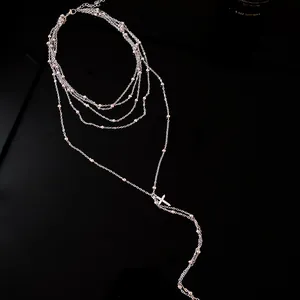Close-up of zircon-encrusted cross pendant on multi-layer silver-toned necklace
