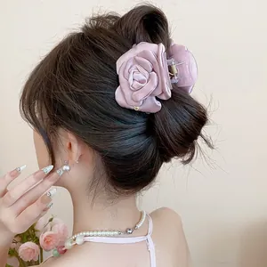 Detailed macro view of an elegant dusty rose satin flower hair claw clip worn on a stylish bun