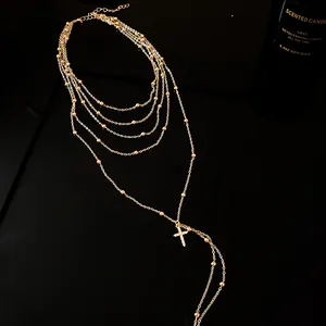 Detailed view of a gold multi-layer necklace featuring a shimmering zircon cross pendant.