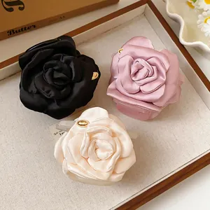 Detailed view of black, pink, and white satin rose hair claws in a tray