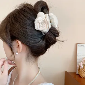 Close-up view of an elegant cream satin rose flower hair claw clip on model's hair