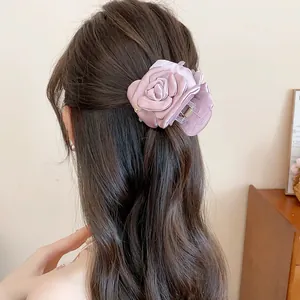 Back view detail of a mauve satin flower hair claw clip styled in wavy brown hair