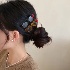 Trendy acrylic apple glasses-shaped side hair clip displayed on model bun hairstyle