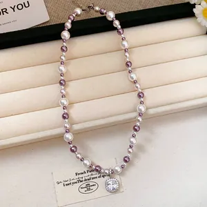 Close-up detail of a French style purple and white pearl necklace with zircon pendant