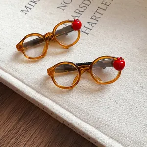 Amber acrylic glasses hair clips with cute red apple accents on textured surface