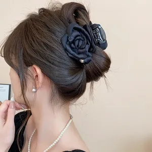 Close-up of a stylish black satin flower hair claw clip worn by a model in detail