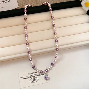 Detailed view of a French style pearl necklace with a pink square zircon pendant