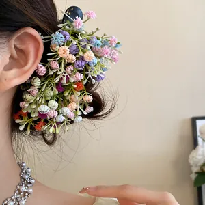 Detailed close-up of a colorful forest style flower cluster hair clip worn on dark hair