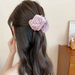 Back view detail of a sweet purple satin flower hair claw clip worn on wavy brown hair