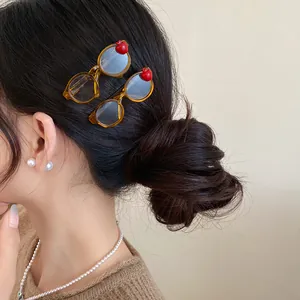 Detailed view of trendy acrylic glasses-shaped hair clips with red apple accents on hair