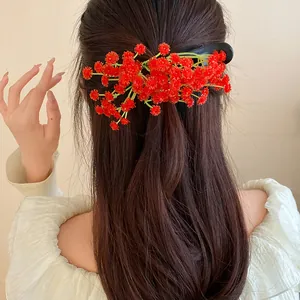 Detailed view of a sweet floral hair clip with red flower clusters worn on brown hair.