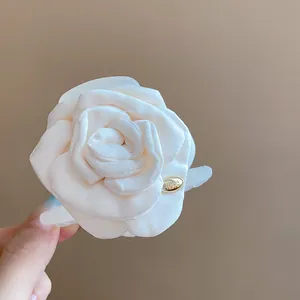 Detailed view of an elegant cream white satin rose hair claw clip with gold LOVE charm