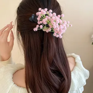 Detail shot of a sweet pink floral cluster duckbill hair clip on long brown wavy hair