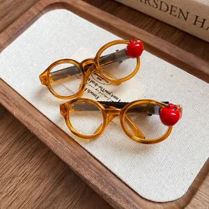 Close-up detail of a trendy orange acrylic round glasses hair clip with a red apple