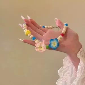 Detail eines farbenfrohen Blumenperlenhalsketten in der Hand mit Spitzenärmel-Detail