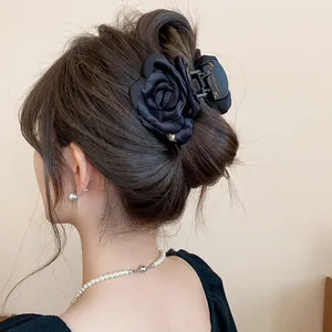 Close-up detail of an elegant black satin rose hair claw clip styled in a classic bun.