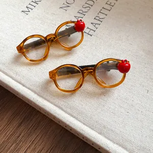 Close-up of two acrylic amber glasses hair clips with red apple accents on a vintage book