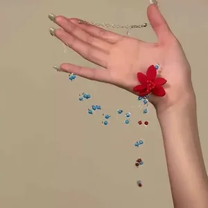 Detailansicht einer handgefertigten Perlenkette mit roter Stoffblume und blauen Perlen