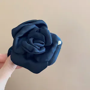 Detail view showing the elegant satin texture of the black rose fabric hair claw clip.