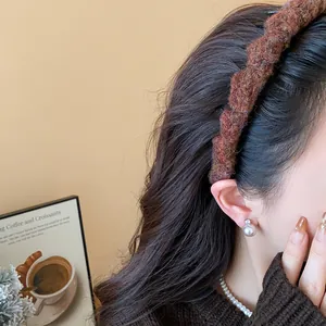 Detailansicht eines braunen Strick-Haarreifens auf Model mit Perlen-Accessoires.