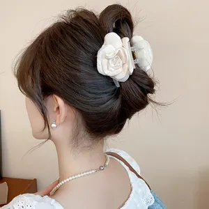 Detailed view of an elegant cream satin rose hair clip styled in a modern hair bun