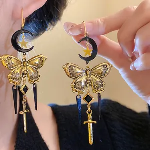 Close-up of vintage gold butterfly and black moon tassel earrings with sword charm