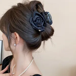 Elegant detail view of a black satin fabric rose hair claw clip worn in a classic updo style