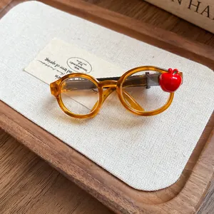 Close-up detail of acrylic glasses hair clip with red apple charm on wooden tray