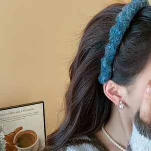 Nahaufnahme eines blau gestrickten Stirnbandes an einem Model mit Perlenohrringen-Detail