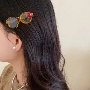 Detail of a creative acrylic hair clip shaped like glasses with a red apple on hair.