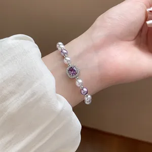 Close-up of elegant French style pearl bracelet featuring a purple square zircon on wrist