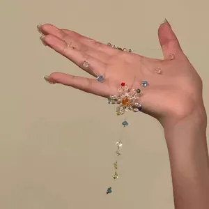 Detailansicht einer bunten Glasperlen-Blumenkette, die in der Hand gehalten wird.