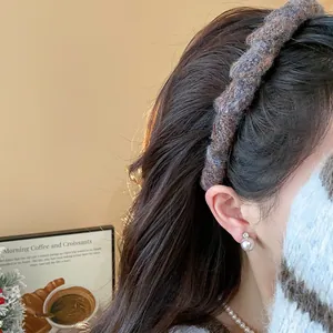 Detailansicht eines grob gestrickten grauen Stirnbandes mit Perlenohrring an asiatischem Model