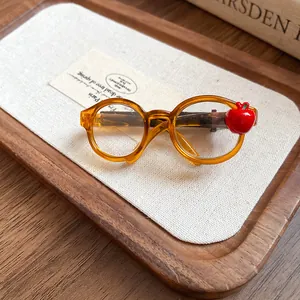 Detail view of amber acrylic glasses-shaped hair clip with red apple charm