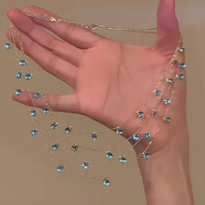 Detailansicht einer mehrreihigen Goldkette mit zarten blauen Glasperlen-Anhängern