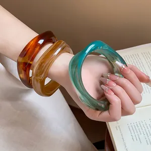 Detail showing three chunky resin bangles with marble dye patterns and smooth finish
