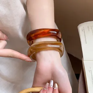 Detailed macro view of stylish chunky square marbled resin bangles worn on a wrist