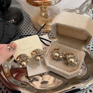 Detailed view of vintage flower and pearl stud earrings displayed in a beige velvet jewelry box