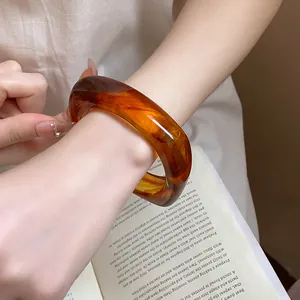 Detailed view of a stylish amber square resin bangle with tortoiseshell patterns on a wrist
